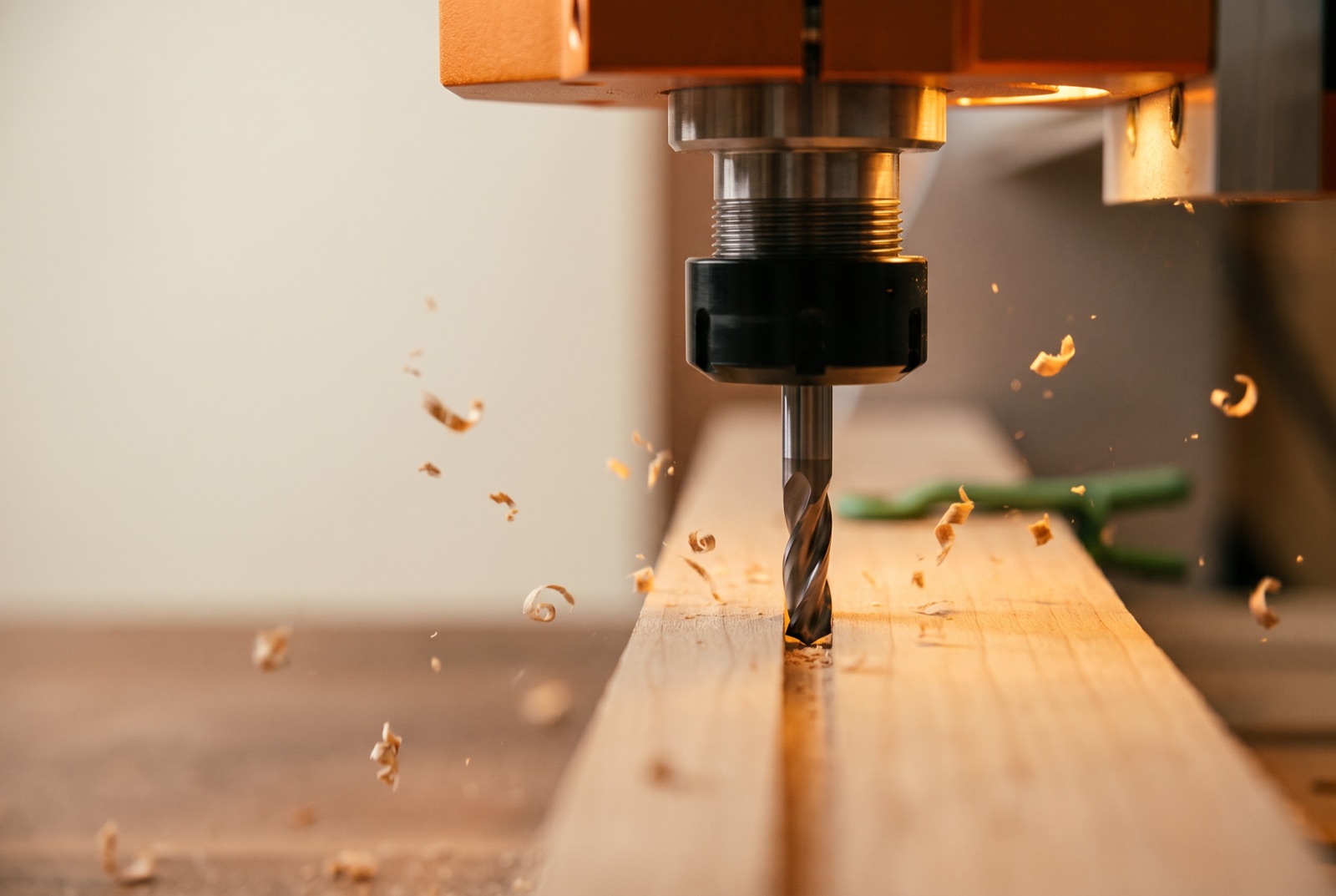 A maple board on a CNC bed with the spindle and V-bit poised at the centre, ready to start a cut.